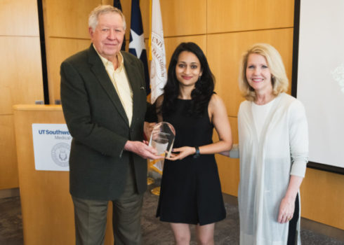 Two people presenting an award to a UTSW student