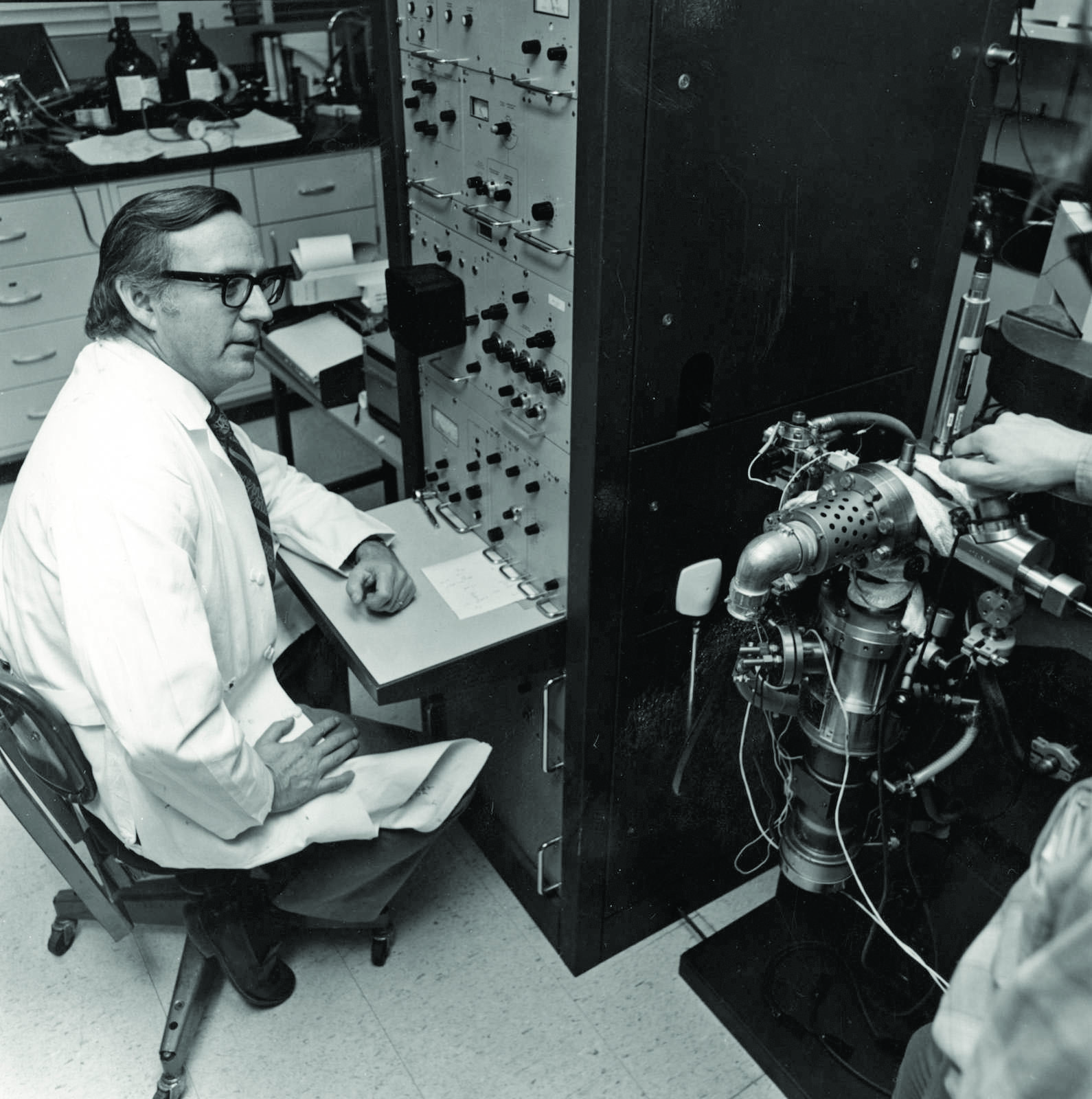 Black and white photo of man sitting in a lab