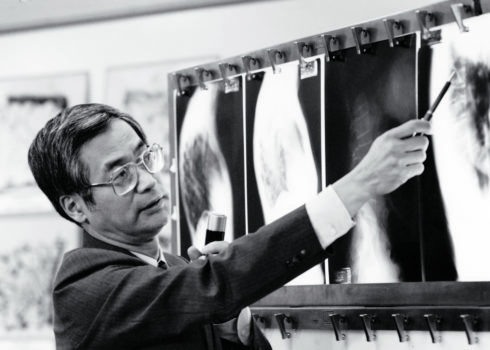 Black and white photo of man in front of an x-ray picture