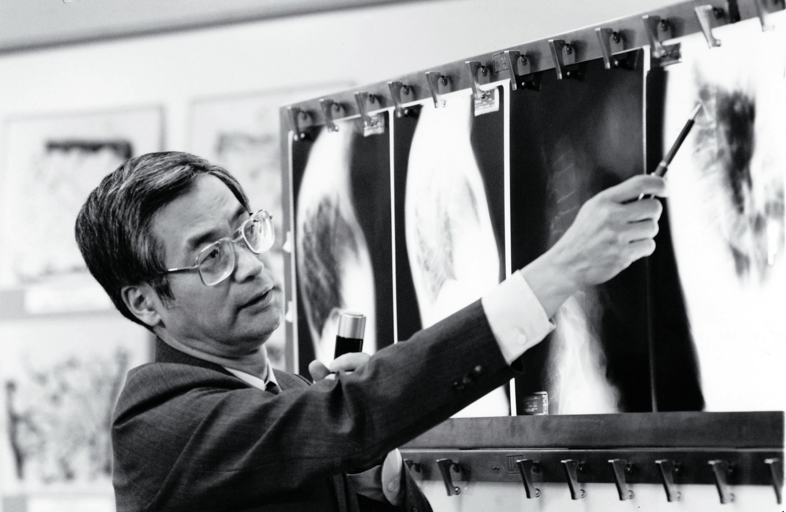 Black and white photo of man in front of an x-ray picture