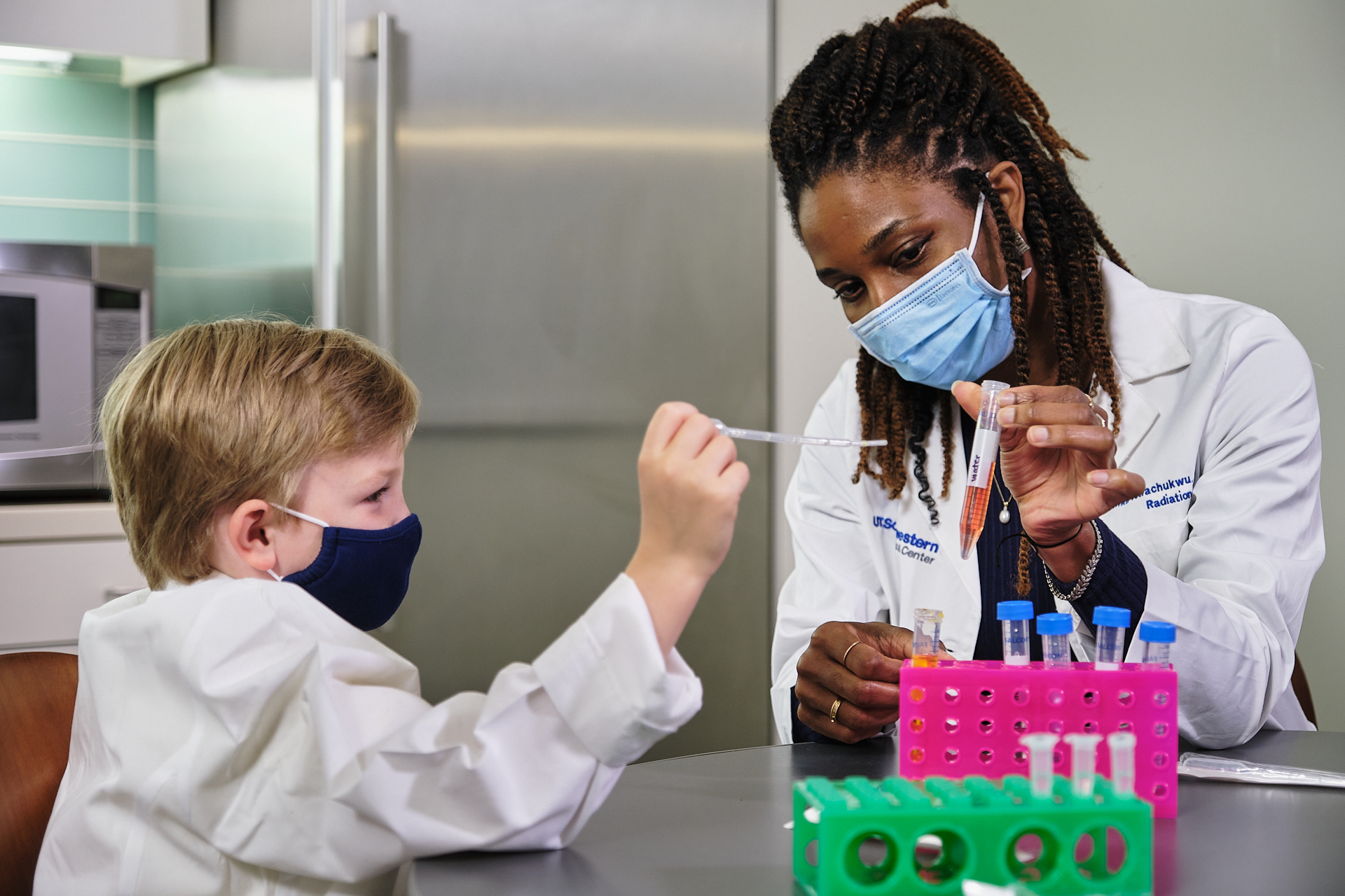 Dr. Chika Nwachukwu showing Hudson Dietz how to do her take-home experiment. Dr. Nwachukwu was awarded an early-stage research grant in support of emerging medical discoveries.
