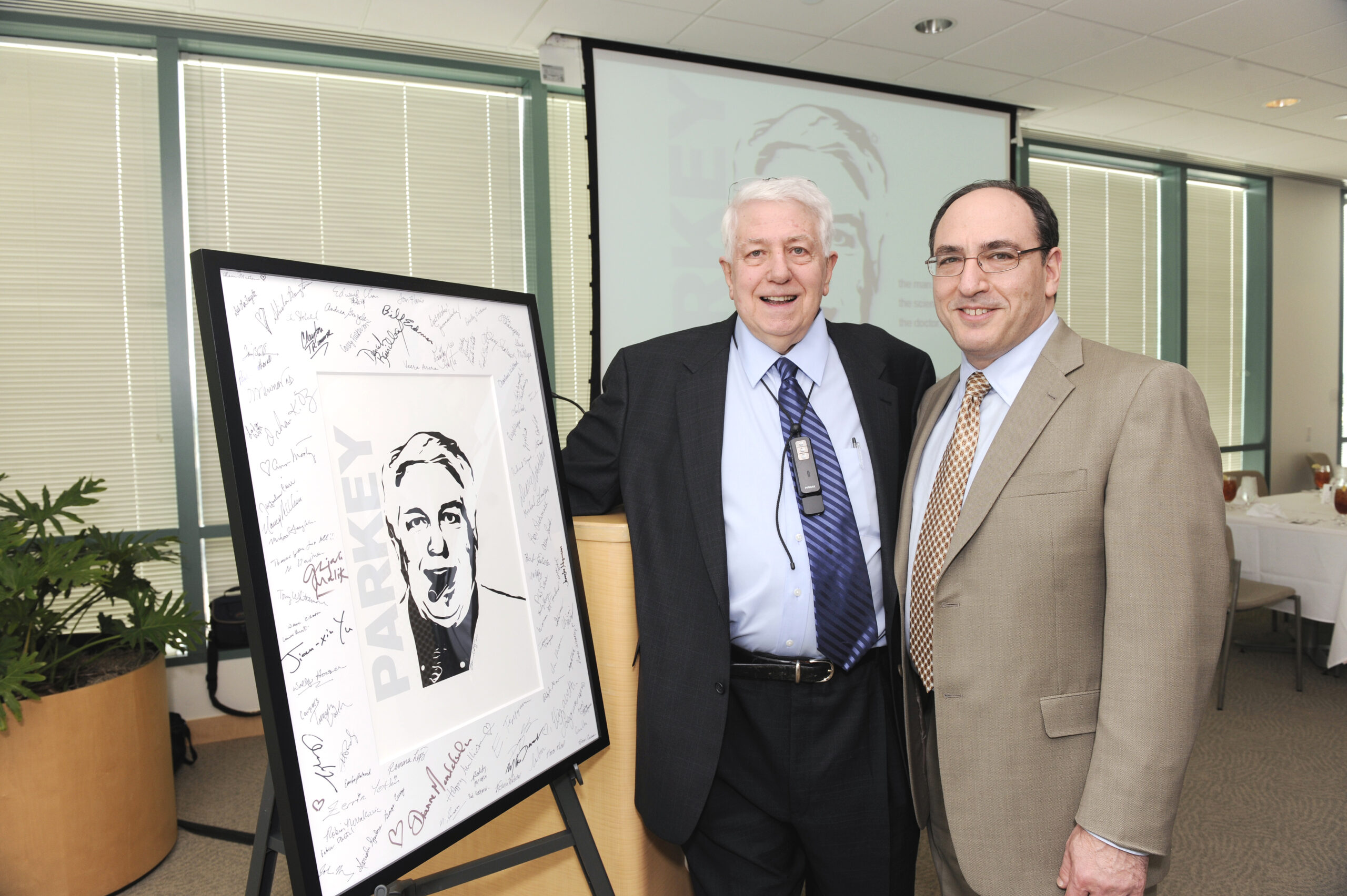 Robert W. Parkey stands next to a piece of artwork in his likeness.