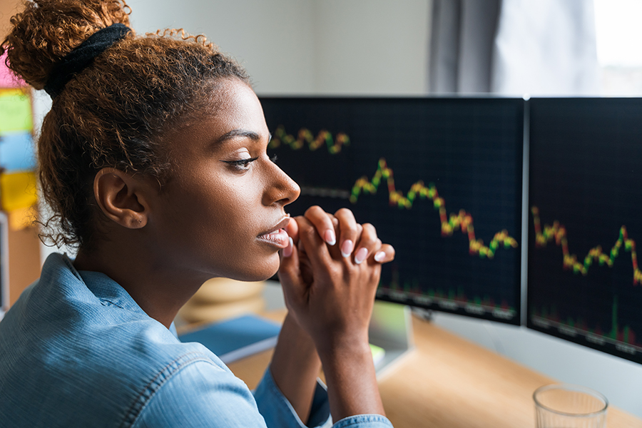 Young woman looking at computer screen showing cryptocurrency price graph.