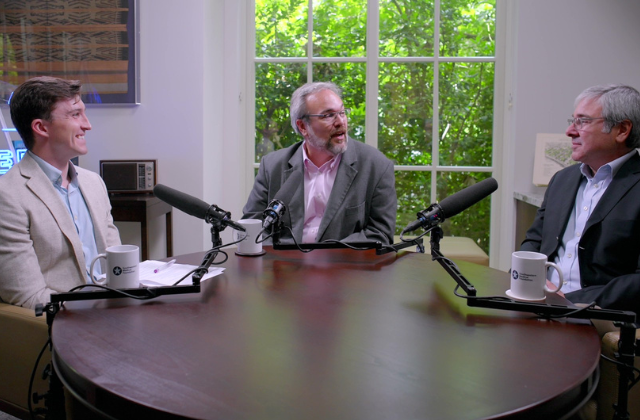 Three men sitting at a table discussing the biotech valley of death